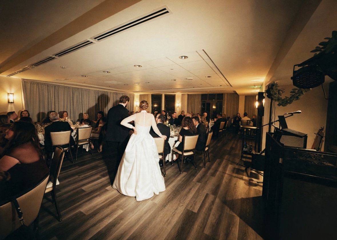 Bride and groom entering their wedding reception as guests watch
