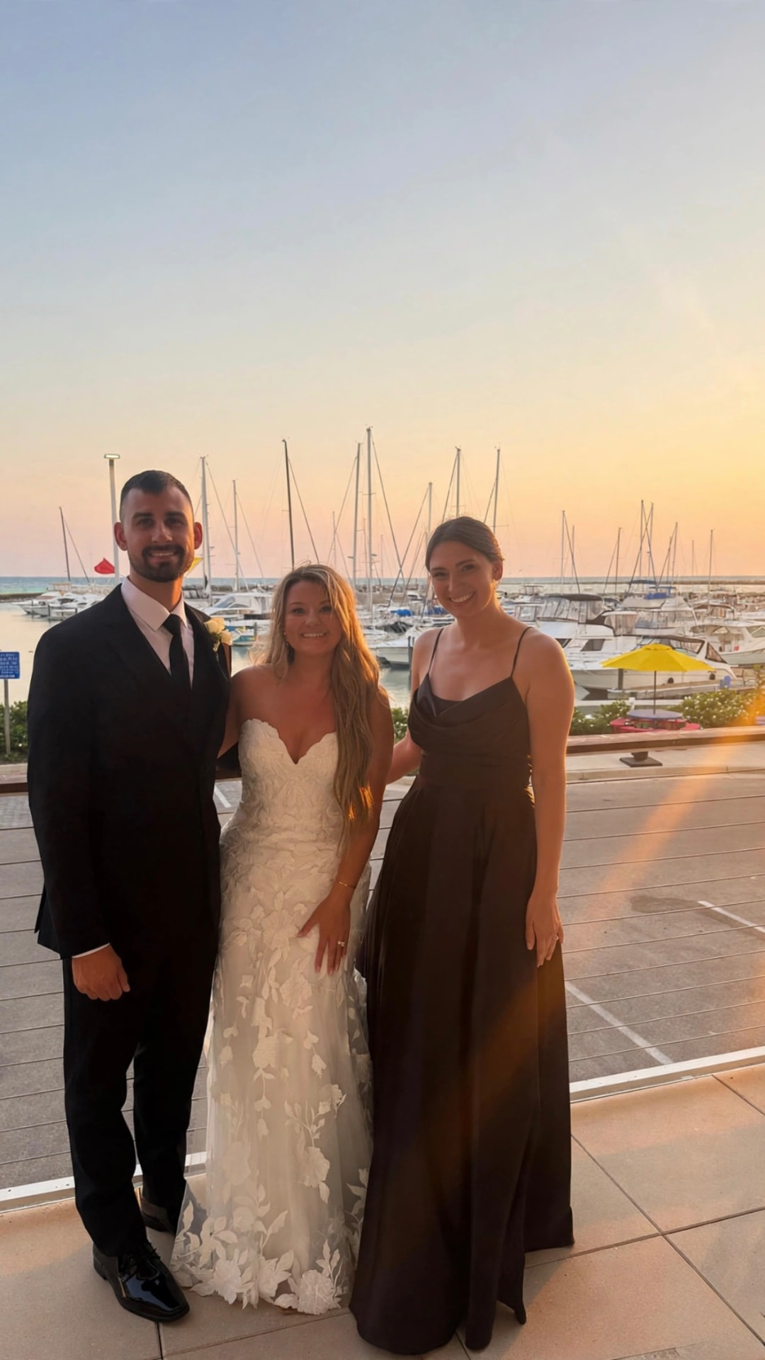 Anna Marie with a bride and groom at a lakeside wedding at sunset