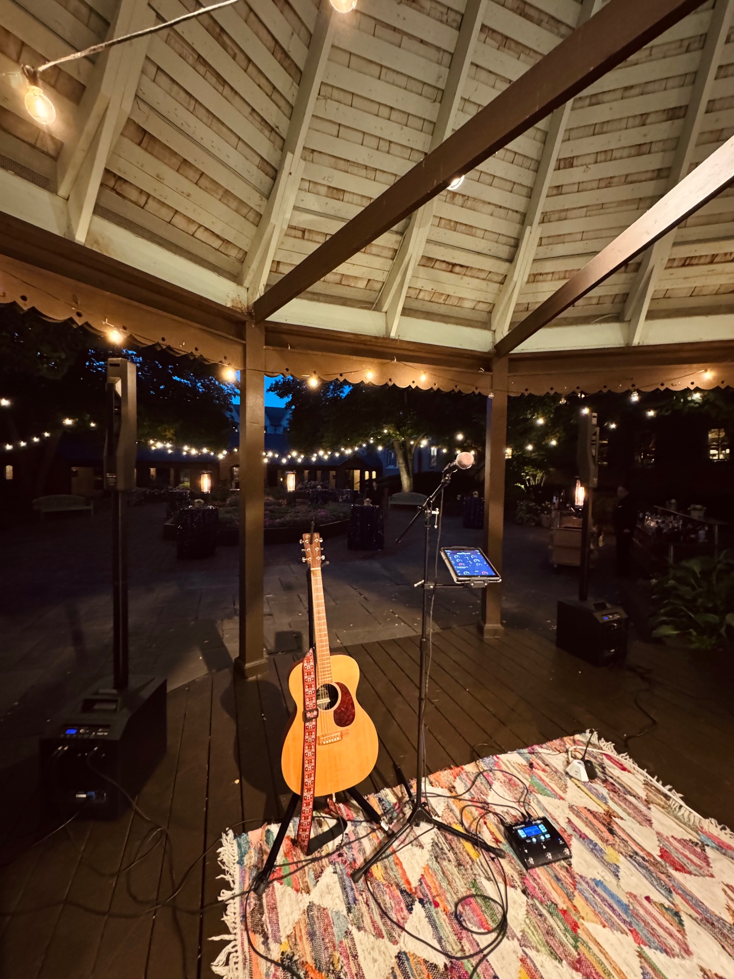 Acoustic guitar set up under string lights at a garden gazebo