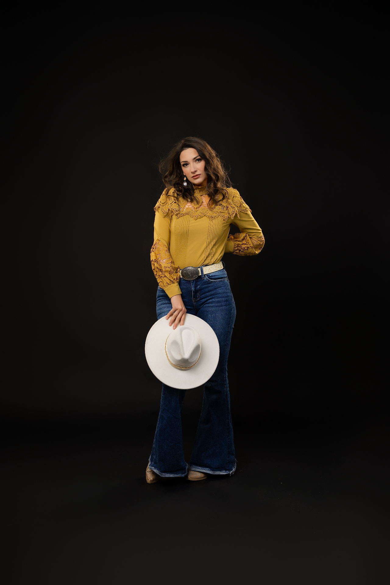Anna Marie in mustard blouse, denim flares, and a white hat